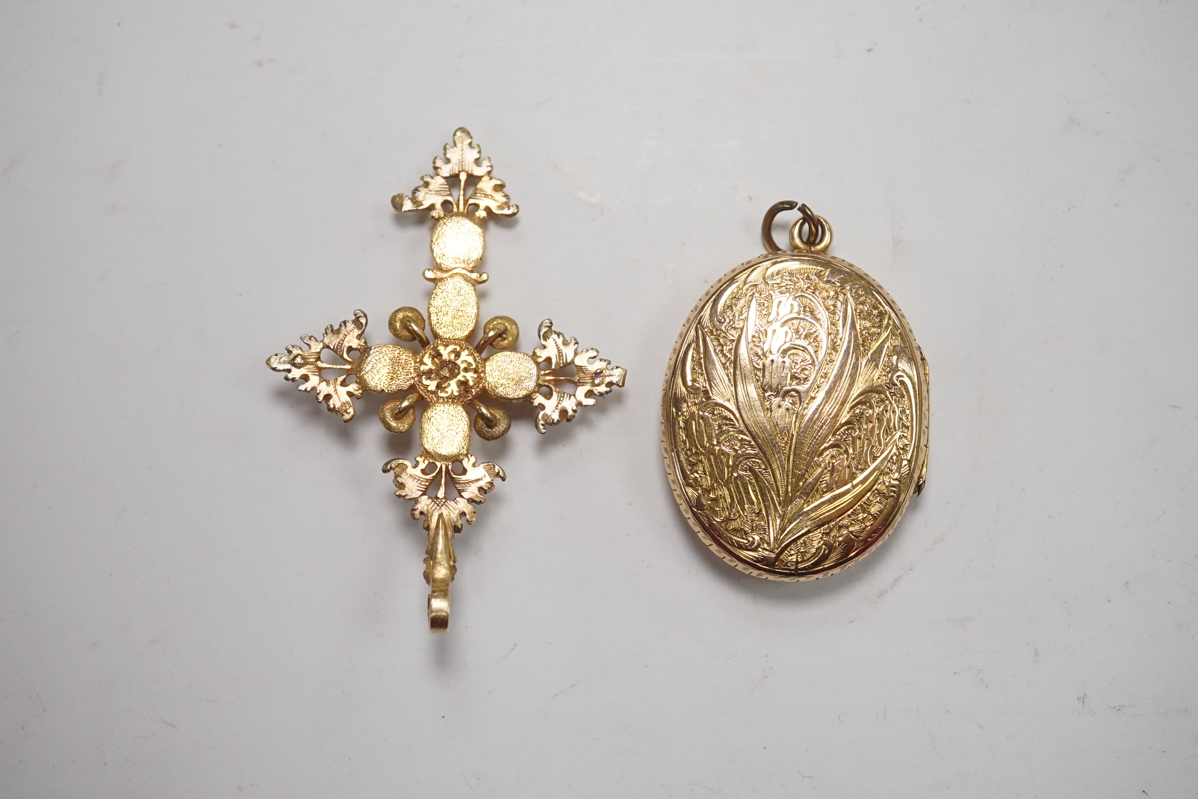 An antique yellow metal and gem set cluster cross pendant, 51mm, together with an engraved yellow metal oval locket. Condition - poor to fair